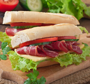 big-sandwich-with-raw-smoked-meat-wooden-background